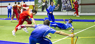 Indoor Cricket wicket keeper breaking stumps with clear view of batsman's bat still short of the crease.
