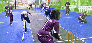 Indoor Cricket front-half action Batswoman stretching to reach crease, but still short as bails are removed